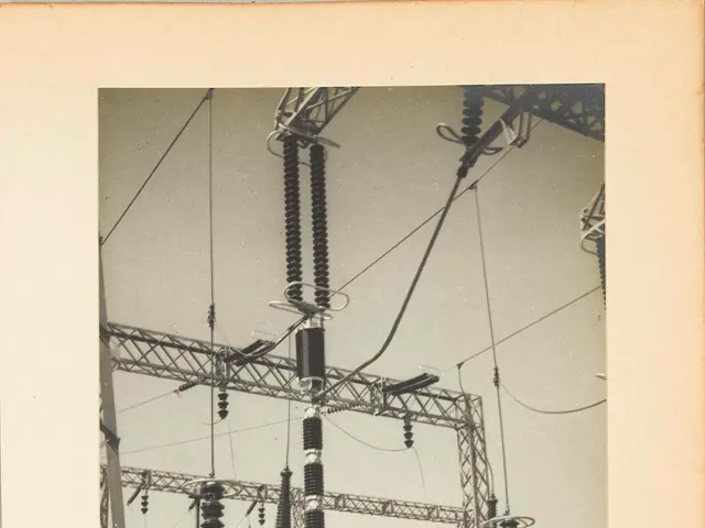 The image shows an old black and white photo of an electrical substation, with transformers and...
