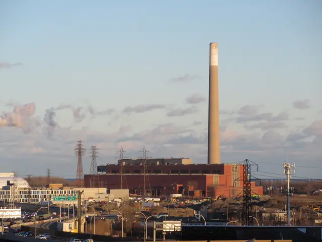The image shows a coal-fired power plant with a large chimney in the middle of a city, surrounded...