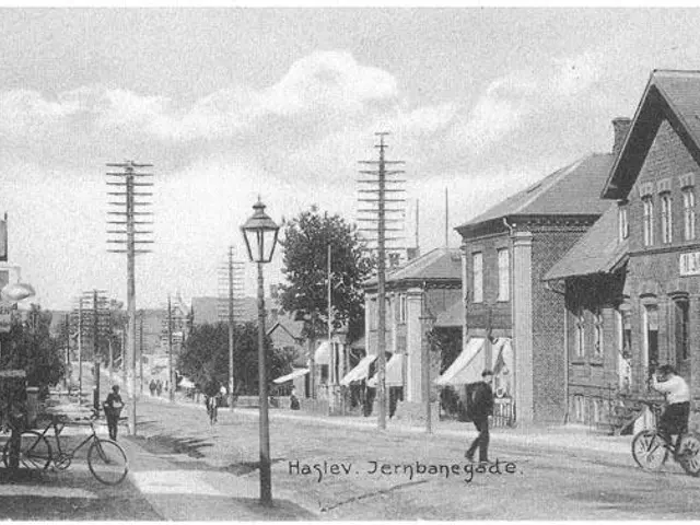 The image shows a black and white photo of a city street with people riding bicycles, electric...