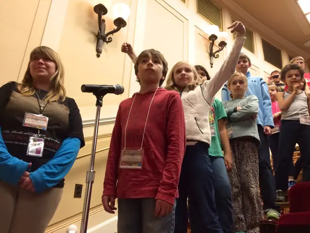 The image shows a group of children standing next to each other in front of a microphone, with a...