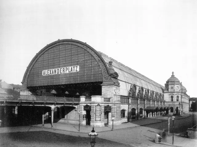 The image shows a black and white photo of Alexanderplatz in Berlin, Germany. It features a large...