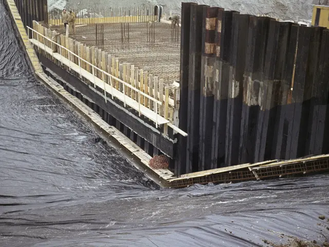 The image shows a construction site with a large body of water, a bridge, a fence, a group of...