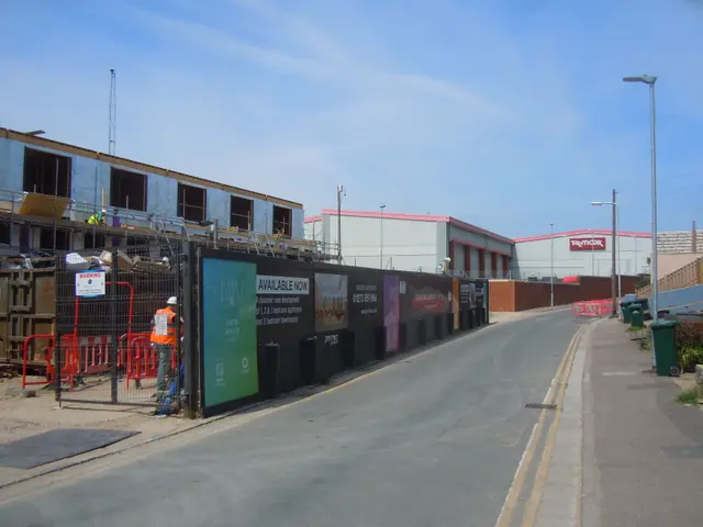 The image shows a road with a sidewalk on the right side, light poles, dustbins, plants, and a...