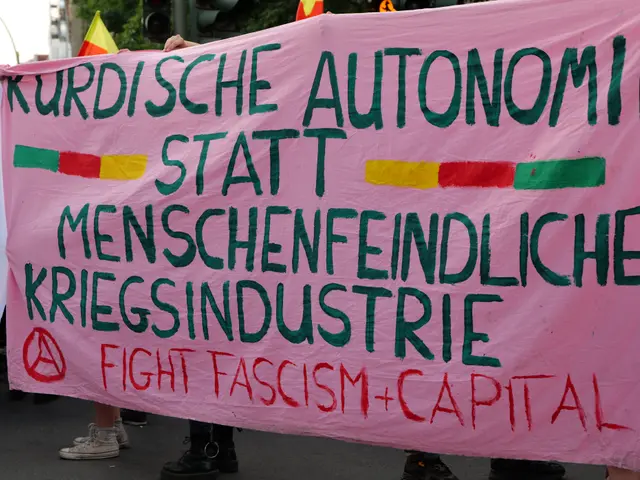 The image shows a group of people standing on the road, holding a pink banner that reads "Kurdische...