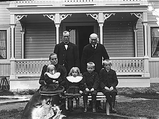 The image shows a black and white photo of a family posing for a picture in front of a house. There...