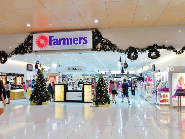 The image shows a group of people walking through a shopping mall decorated for Christmas. There...