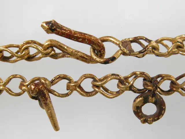 The image shows a close up of a gold chain with a lock on it against a white background. The chain...