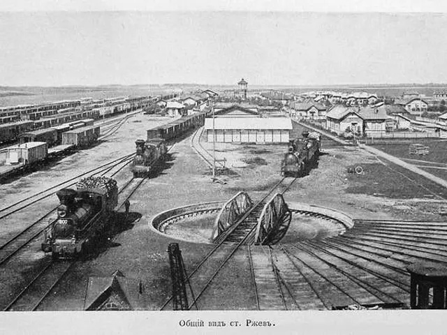 The image shows an old black and white photo of a train station with several trains on the railway...