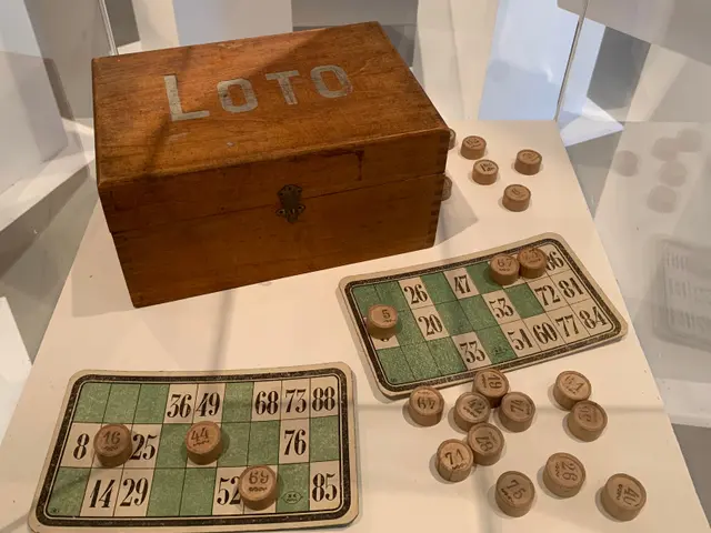 The image shows a wooden box with the word "Loto" on it, sitting on a table with a board and some...