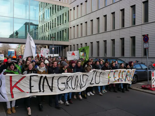 The image shows a group of people standing on the road, holding a banner that reads "Kein Grind Lo...
