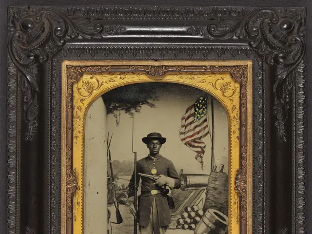 The image shows an old photo of a confederate soldier wearing a hat and holding a rifle, standing...