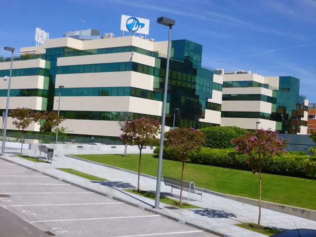 The image shows a large building with a lot of windows in front of it, surrounded by street poles,...