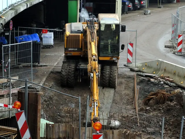 The image shows a construction site with a large excavator in the middle of it, surrounded by a...