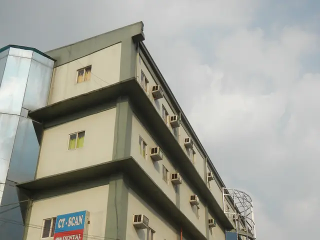 The image shows a building with windows, air conditioners, a sign that reads "Now Hiring...