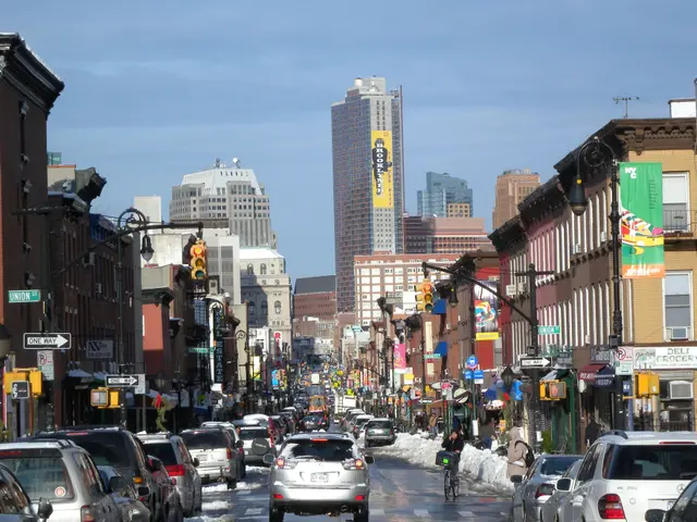 The image shows a city street filled with lots of traffic on a snowy day. We can see vehicles on...