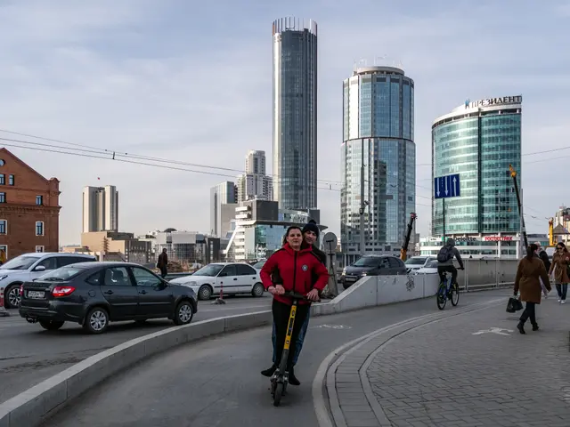 The image shows a man riding an electric scooter down a street lined with tall buildings. He is...