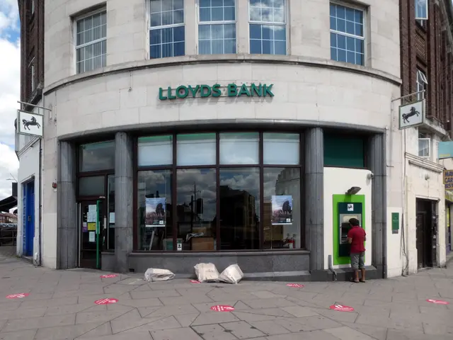 The image shows a Lloyds Bank branch in London, England. There is a person standing in front of the...