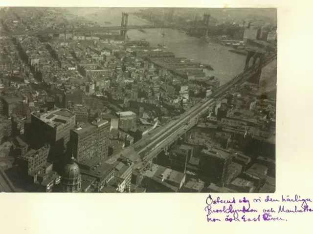 The image shows an old black and white photo of a city with a bridge in the background. There are...