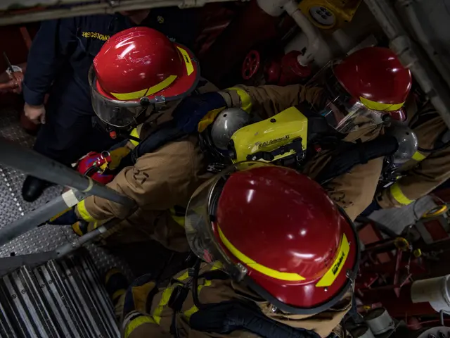 The image shows a group of firefighters wearing helmets and protective gear, working on a fire...