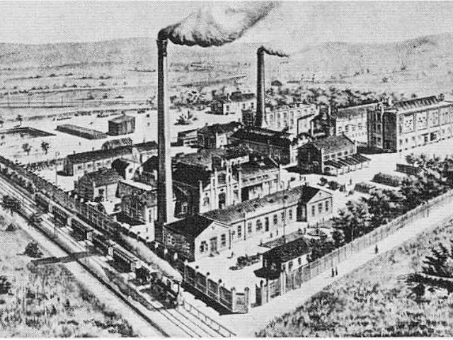 The image shows an old black and white drawing of a factory with smoke coming out of its chimneys,...