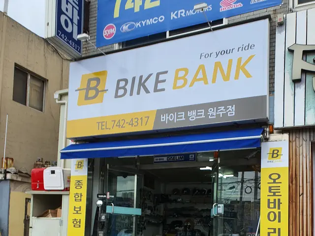 The image shows a bike shop with a sign that reads "Bike Bank" on the side of it. There are...