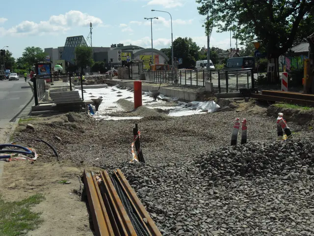 The image shows a construction site with a lot of construction equipment on the side of the road,...