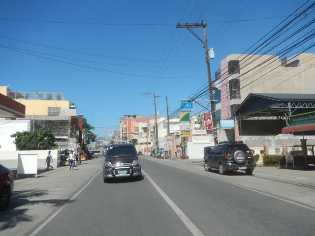 The image shows a city street with cars driving down it, people walking on the sidewalk, electric...