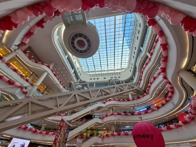 The image shows the inside of a shopping mall decorated for Valentine's Day with pink and white...