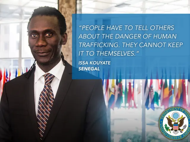The image shows a man in a suit and tie standing in front of flags, with a logo and text on the...