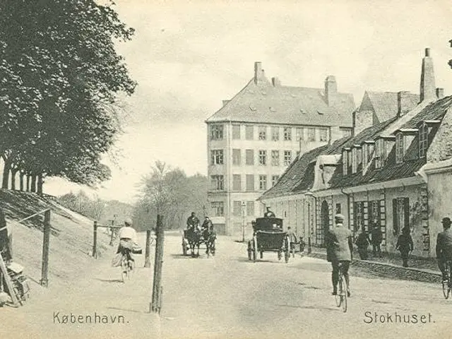 The image shows an old black and white photo of people riding bicycles down a street in Stokhuset,...
