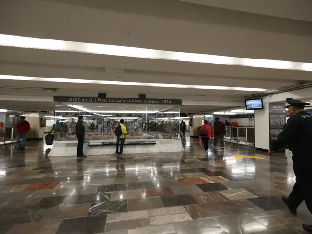 The image shows a group of people walking through a subway station, with a police officer in the...