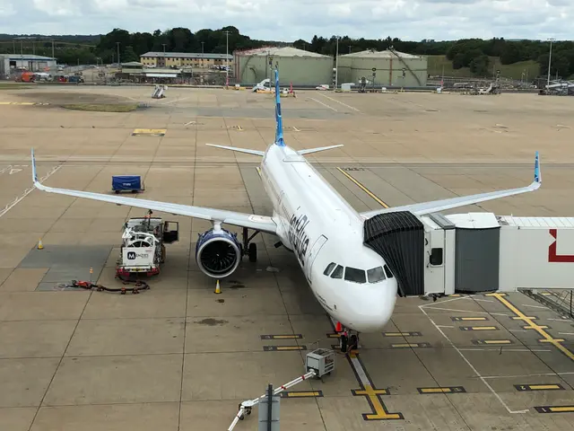 The image shows a large jetliner sitting on top of an airport tarmac, surrounded by vehicles,...