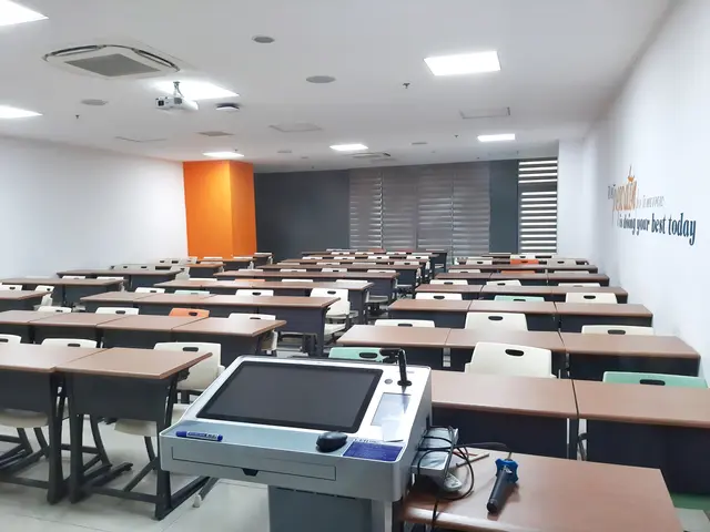 The image shows a classroom with desks and chairs arranged in neat rows, a projector on the...