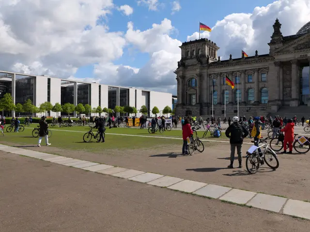 The image shows a group of people riding bicycles in front of the Reichstag building in Berlin,...
