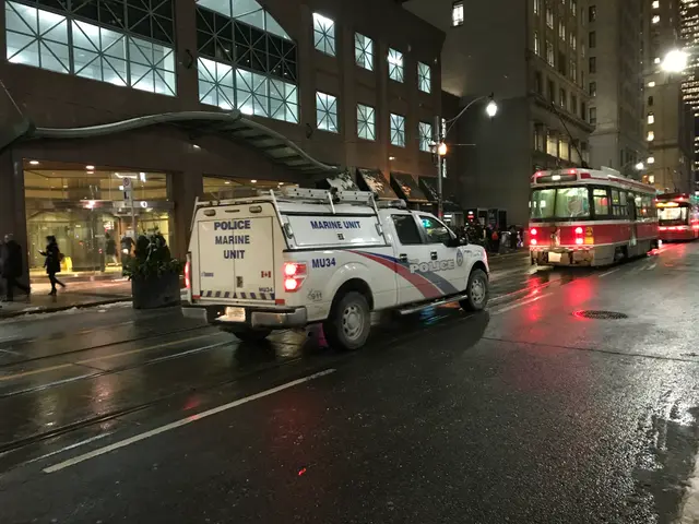 The image shows a police truck parked on the side of a city street at night. We can see vehicles on...