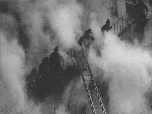 The image shows a group of firefighters on a ladder in front of a building, with smoke billowing...