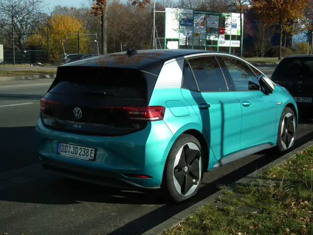 The image shows a blue Volkswagen e-Golf parked on the side of a road, surrounded by grass and dry...