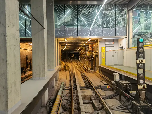 The image shows a train station with a train on the tracks, illuminated by lights at the top. On...