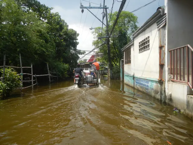 The image shows a man riding a motorcycle through a flooded street in Manila, Philippines. On the...