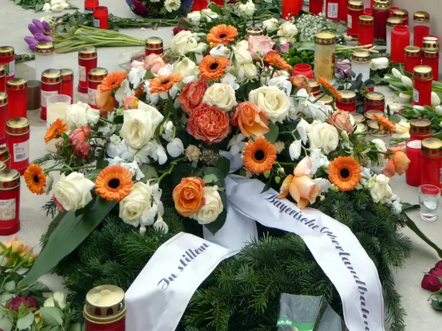 The image shows a memorial in Berlin, Germany, with a bunch of flowers and candles placed on the...