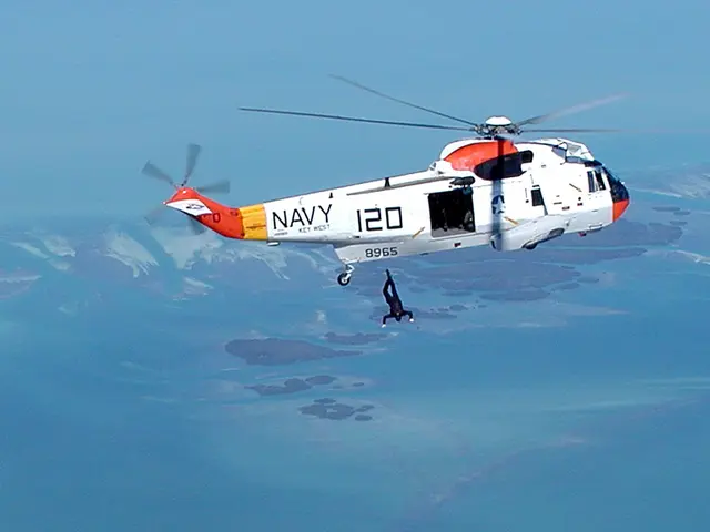 The image shows a helicopter flying over a body of water with a person in the air, and the sky is...