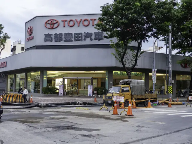 The image shows a Toyota dealership in Tokyo, Japan, with vehicles on the road, traffic cones,...