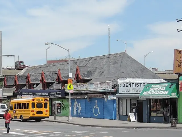 The image shows a city street with a yellow school bus driving down it, surrounded by buildings,...