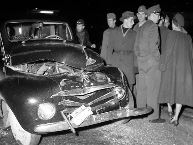 The image shows a black and white scene of a car that has been involved in a crash on the side of...