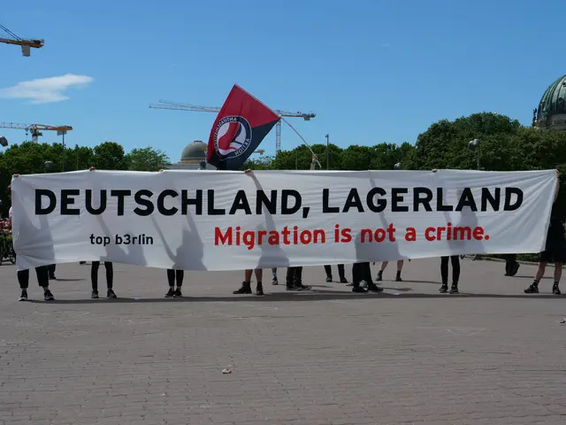 The image shows a group of people standing on the ground, holding a banner that reads "Deutschland,...