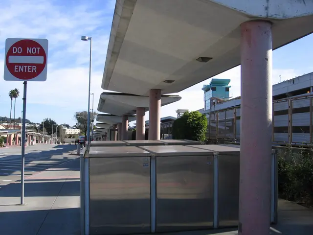 The image shows a bus stop with a sign that reads "Do Not Enter" on the side of the road. There are...