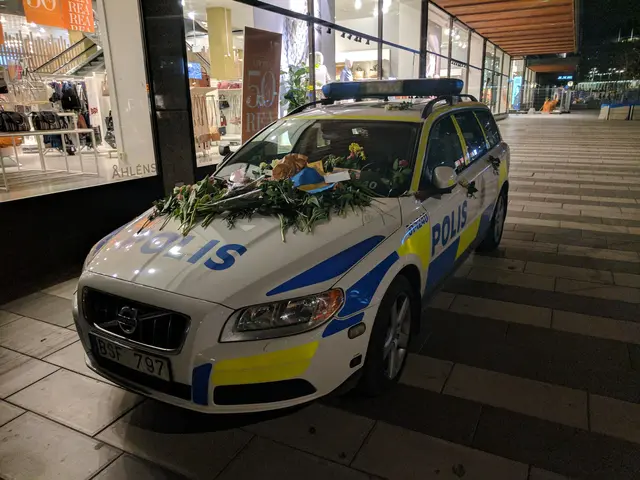 The image shows a police car parked in front of a store at night. The car is decorated with flowers...