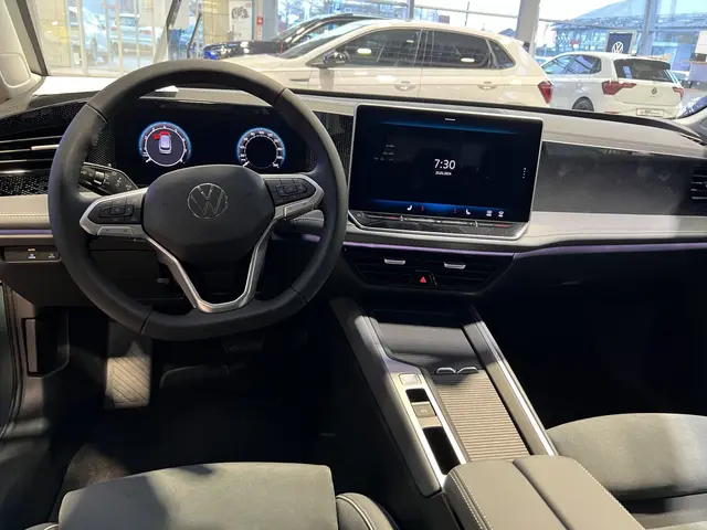 The image shows the interior of a Volkswagen e-Golf, with a steering wheel, dashboard, screens,...