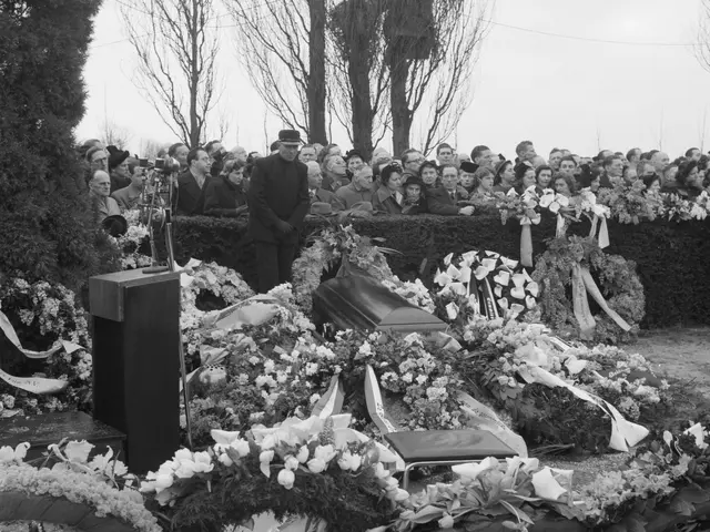 The image shows a black and white scene of a funeral procession with a man standing at a podium in...