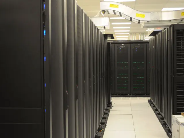 The image shows a data center with a row of servers in it, illuminated by lights on the ceiling....